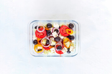 Lunch box with greek salad on white background