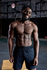 Fototapeta na wymiar Portrait of fit strong muscular afro american male with naked torso posing at camera and smiling, in gym indoors,handsome black guy having rest after training, workout. people, sport, lifestyle