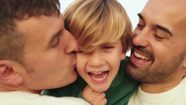 Gay male couple having tender moment with boy outdoor - LGBT family love concept