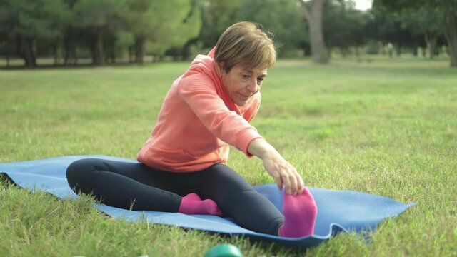 Senior woman doing yoga sport routine at city park