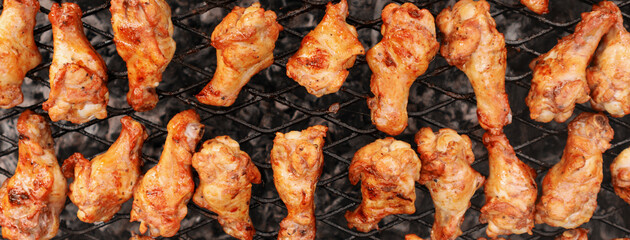 Banner with chicken wings. Grilled brown meat on the grill. Grilling meat on coals. Soft focus