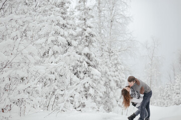 Fototapeta na wymiar Hipster couple in love hugs each other in a winter park. Winter holidays. Christmas holidays outdoors in the forest. Copy space