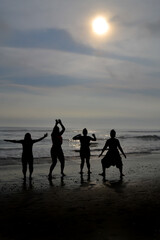 Silhouette of 4 women jumping on a beach at sunset