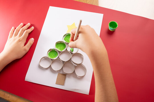 baby hand drawing Christmas tree, paper craft made of empty toilet paper roll