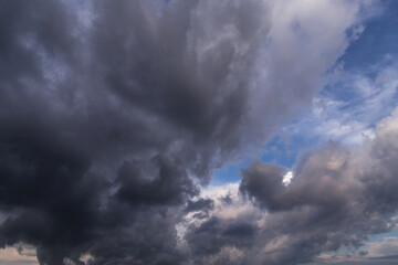 Obraz premium Dramatic storm dark grey cumulus rain clouds against blue sky background texture