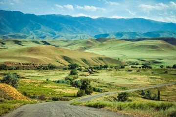 Beautiful landscape of green rolling grass land and stone mountains along the road landscape