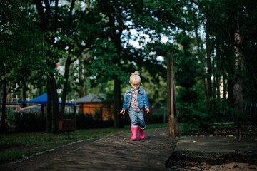 
little cute girl in pink rubber boots on a walk in spring