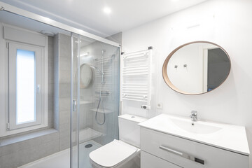 Obraz na płótnie Canvas Toilet with shower and wall-mounted radiator in white tones with round mirror