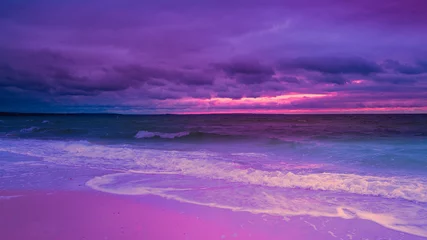Wall murals Violet Moody stormy seascape at sunset over the Buzzard Bay on Cape Cod in winter. Saturated vibrant pink and green twilight landscape on the beach. Curving white waves rolling in on the tropical beach.