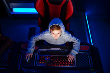 Top view of caucasian boy gamer playing video games on computer in game room. Children's addiction to virtual games and entertainment.