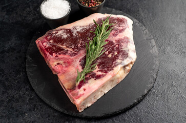 Raw t-bone steak with spices on a stone background. dry-aged steak