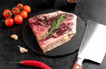 Raw t-bone steak with spices on a stone background. dry-aged steak