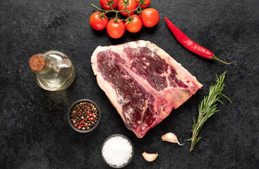 Raw t-bone steak with spices on a stone background. dry-aged steak