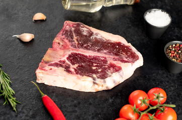 Raw t-bone steak with spices on a stone background. dry-aged steak