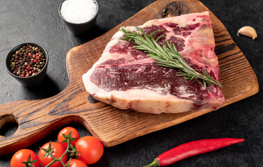 Raw t-bone steak with spices on a stone background. dry-aged steak