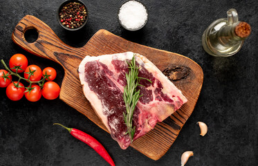 Raw t-bone steak with spices on a stone background. dry-aged steak