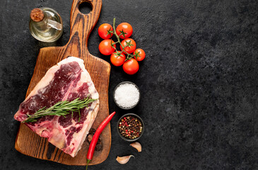 Obraz na płótnie Canvas Raw t-bone steak with spices on a stone background. dry-aged steak with copy space for your text 