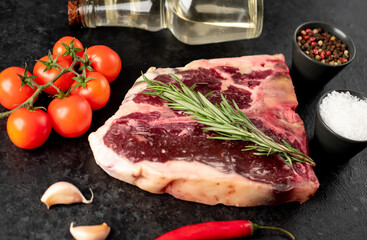 Raw t-bone steak with spices on a stone background. dry-aged steak