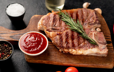 grilled t-bone steak with spices on a stone background