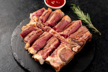 grilled t-bone steak with spices on a stone background