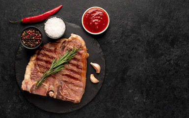 Fototapeta na wymiar grilled t-bone steak with spices on a stone background with copy space for your text