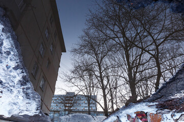 Abstract photography. Reflection in a spring puddle. Residential high-rise buildings are reflected in a puddle on the asphalt.