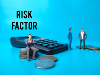 Miniature people,calculator and coins with text RISK FACTOR on a blue background.