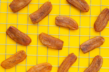 Sun dried bananas on yellow background.