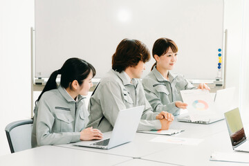 会議をする作業着をきた会社員（提案・3人）
