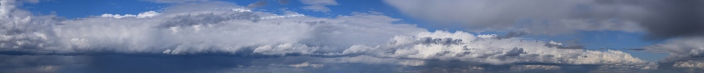 Noon, summer cumulus clouds before rain.
Panoramic, horizontal, photographic image of the sky, water vapor, atmospheric phenomenon. - 471602845