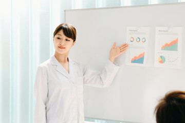 説明する白衣姿の女性
