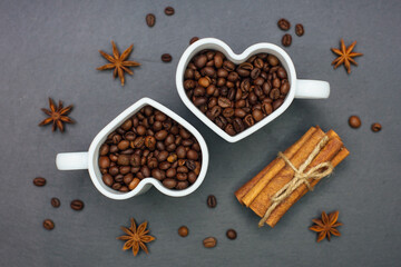 Roasted Coffee beans in heart shape cups with cinnamon sticks. Top view.