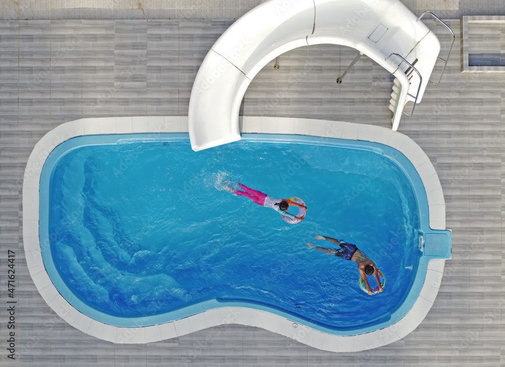 Wall mural Children play in the outdoor pool on a family vacation.