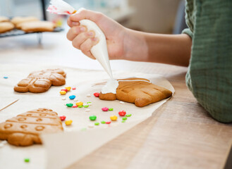 Child is decorating honey gingerbread cookies on table at kitchen. Icing of Christmas bakery.
