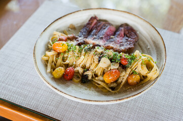 Aglio e olio with grilled meat on ceramic dish