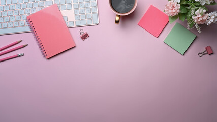 Female workplace with notebook, coffee cup and sticky notes on pink background.