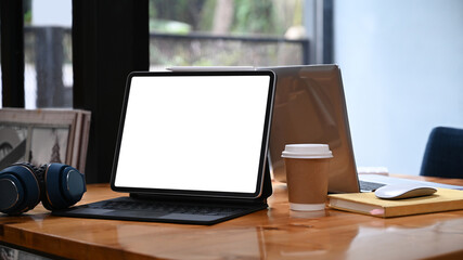 Mock up computer tablet, coffee cup and wireless headphone on wooden table.
