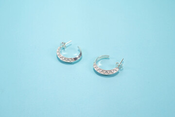 Tribal silver earrings on pastel blue background