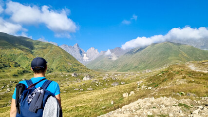 A man watching the sharp mountain peaks of the Chaukhi massif in the Greater Caucasus Mountain...
