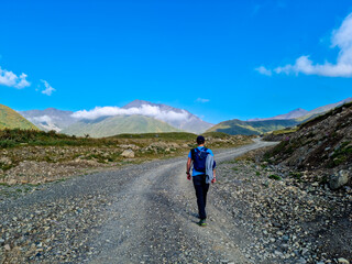 A man walking on a hiking trail with a view on the sharp mountain peaks of the Chaukhi massif in the Greater Caucasus Mountain Range in Georgia, Kazbegi Region. Remedy, Wanderlust.Georgian Dolomites