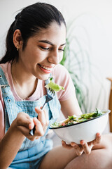 young latin woman eating vegetable or salad bowl, healthy food at home in Mexico Latin America