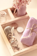 Obraz na płótnie Canvas Lilac-colored towel, bottle of lavender herbs and essential oil on a wooden tray. Spa background, Body care, flat lay
