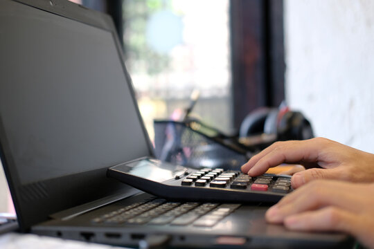 businesswoman working out her finances with a calculator and a notepad in her office