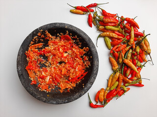 Sambal or traditional chili sauce from Indonesia, freshly made using stone mortar and pestle, with whole bird's eye chili on the side