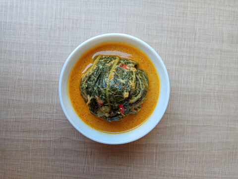 Buntil, traditional Javanese food, made from papaya leaves, with filling anchovy fish and grated coconut inside, shaped like a ball. With spicy coconut milk as dressing.