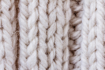 Creamy knitted warm clothes for winter, fabric texture background, close up