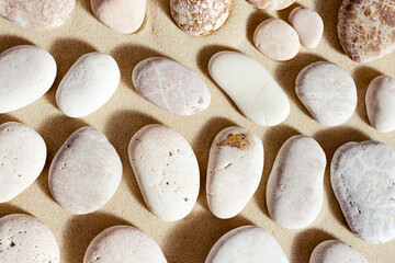 Aesthetic minimal pattern with set of pebble stones on fine sand background. Top view on natural...