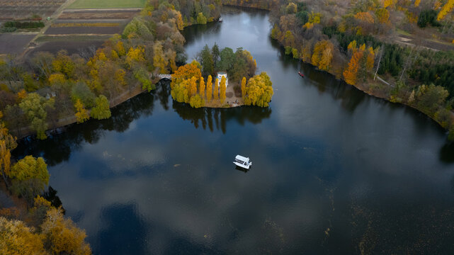 Island with white gazebo in an Autumn park Lake. White yacht or boat near the island. View from above. Sofiivka, Uman, Ukraine.