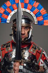 Proud roman soldier with gladius posing against gray background