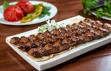 Fast food. Eastern food. Shish kebab, lyulya-kebab. Dishes of oriental cuisine lying in plte and decorated with greens and vegetables, sauces